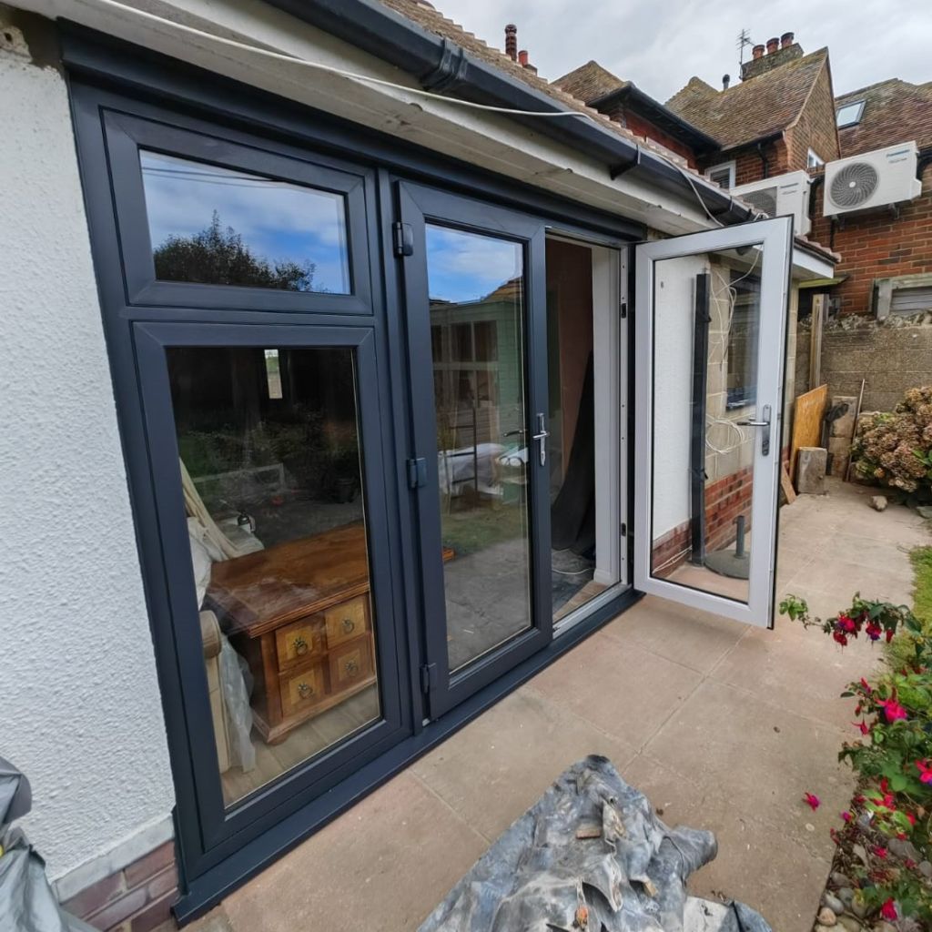 Exterior view of grey outside, white inside John Fredericks PVC-u French doors with a side window featuring a fanlight opener